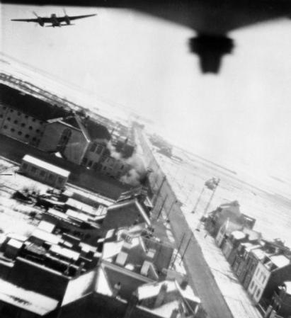 Mosquitos of No. 487 Squadron RNZAF clear the target at low level as the first 500-lb bombs to be dropped detonate near the south wall of the prison